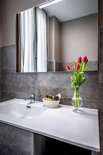 a bathroom sink with a vase of tulips and a mirror at La Corte di Ripoli in Bagno a Ripoli