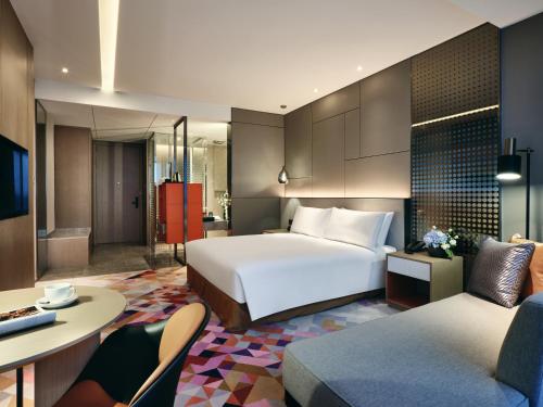 a hotel room with a bed and a living room at The QUBE Hotel Ningbo North in Ningbo