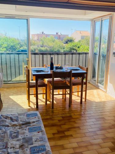une salle à manger avec une table et des chaises et une grande fenêtre dans l'établissement A 70 metres de la plage, etage 1, au Cap d'Agde