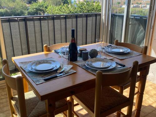 - une table en bois avec des assiettes et une bouteille de vin dans l'établissement A 70 metres de la plage, etage 1, au Cap d'Agde