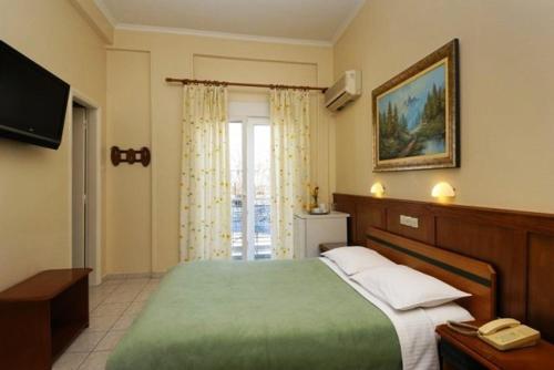 a bedroom with a green bed and a television at Hotel Admitos in Volos