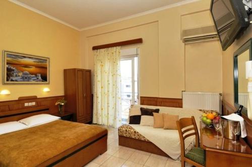 a bedroom with a bed and a desk and a television at Hotel Admitos in Volos