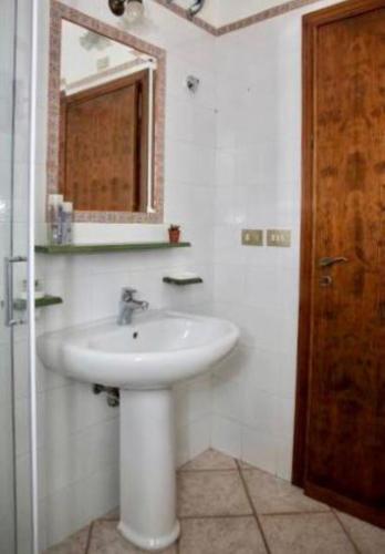 a white bathroom with a sink and a mirror at casa Maruzza in Casteldaccia