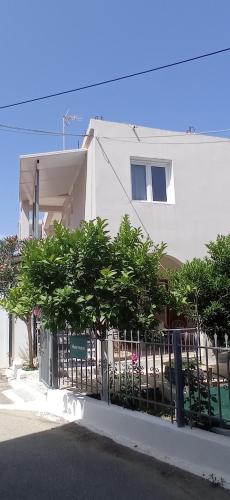 a fence in front of a white building with trees at Hermes in Kavos