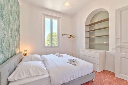 a white bedroom with a bed and a window at Maison Martel in Antibes
