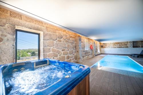 Una gran bañera azul en una habitación con una pared de piedra. en Botica House, en Póvoa de Lanhoso