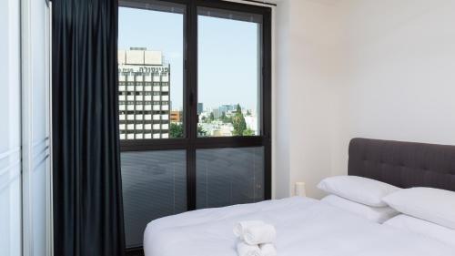 a bedroom with a bed and a large window at Renovated 3BR Penthouse by HolyGuest in Tel Aviv