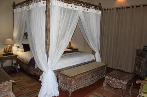 a bedroom with a canopy bed with white curtains at N'taba River Lodge & Spa in Port St Johns