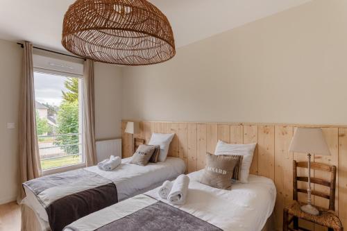 two beds in a room with a window at La Cabane des Ebihens - A moins d'1km de la plage in Lancieux