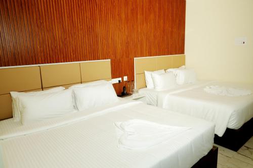 two beds in a hotel room with white sheets at Hotel Dusk and Dawn in Rāmeswaram