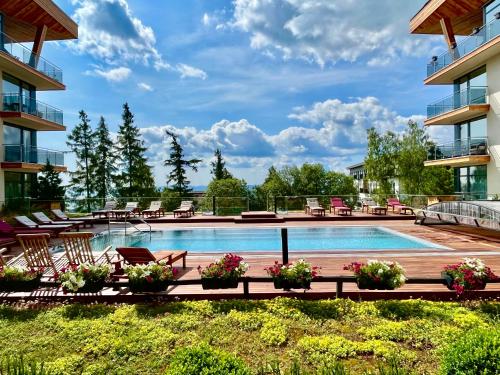 a swimming pool at a hotel with chairs and flowers at Hotelový apartmán ALFRED C407 in Vysoke Tatry - Stary Smokovec