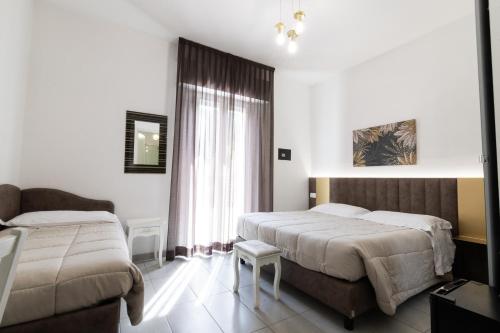 a hotel room with two beds and a window at Villa Liliana in Cervia