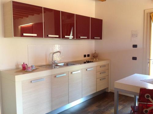 a kitchen with brown cabinets and a sink and a table at Relais Villa Annamaria Bed end Breakfast in Istrana