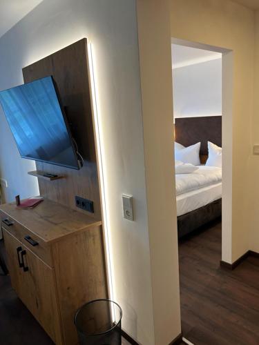 a room with a bedroom with a bed and a flat screen tv at Hotel Schwaiger in Glonn