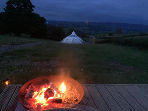 a fire pit with a tent in the background at Luxury Stargazing Glamping - Seren Aur with Hot Tub in Llanidloes