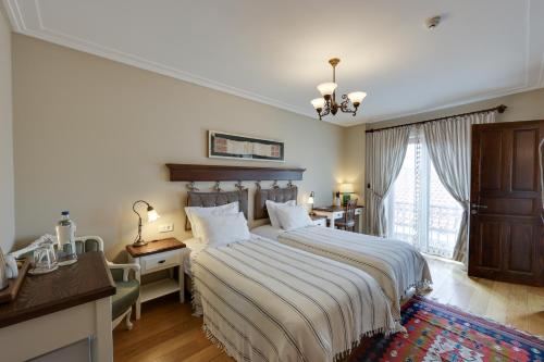 Schlafzimmer mit einem Bett, einem Schreibtisch und einem Fenster in der Unterkunft Akanthus Hotel Ephesus in Selçuk