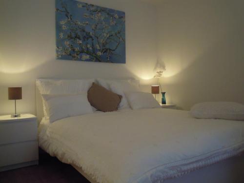 ザントフォールトにあるAppartement Seabirdの白いベッド1台付きのベッドルーム1室(壁に絵画付)