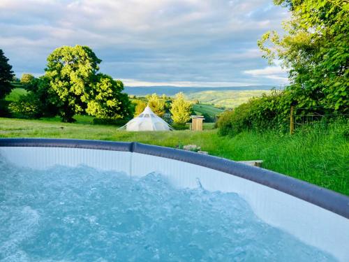 a hot tub in a yard with a tent in the background at Luxury Stargazing Glamping - Seren Aur with Hot Tub in Llanidloes