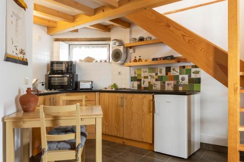 a kitchen with wooden cabinets and a table and a refrigerator at Cerdeira - Home for Creativity in Lousã