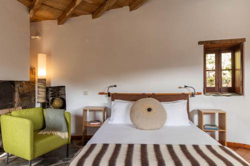 a bedroom with a bed and a green chair at Cerdeira - Home for Creativity in Lousã