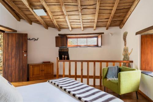a bedroom with a bed and a chair at Cerdeira - Home for Creativity in Lousã
