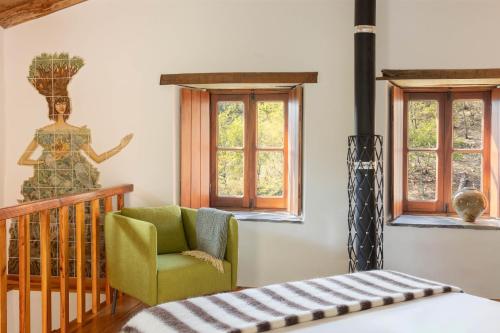 a bedroom with a bed and a chair and windows at Cerdeira - Home for Creativity in Lousã