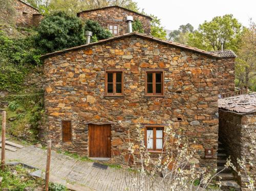 an old stone house with a wooden door and windows at Cerdeira - Home for Creativity in Lousã