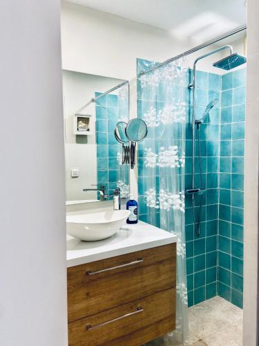 une salle de bain avec un lavabo et une douche avec du carrelage bleu dans l'établissement La maison bleue, à Mollégès