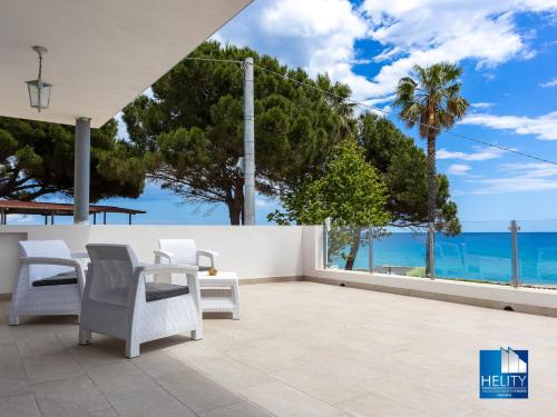 a patio with a table and chairs and the ocean at CALALUNGA PIETRAGRANDE - Exclusive Shoreline Haven in Montepaone Lido