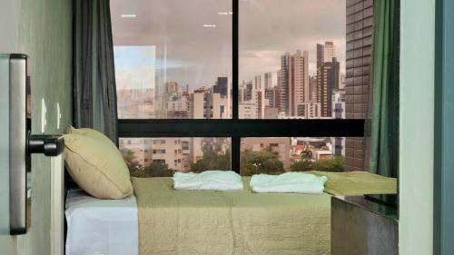 a bed in a room with a large window at Studio Flat Tramonto in João Pessoa