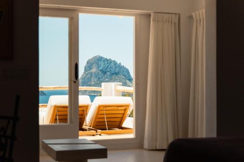 a room with a window with a view of the ocean at Petunia Ibiza, a Beaumier hotel in Cala Vadella