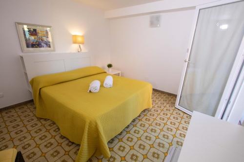 a room with a yellow bed with two towels on it at Le Torrette Rooms and Apartments in Avola