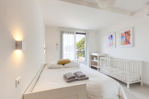 - une chambre blanche avec un lit et un lit bébé dans l'établissement Villa Romy - calme & piscine chauffée, à Sanary-sur-Mer
