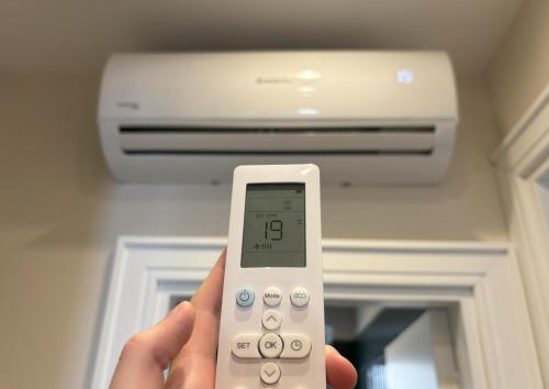 a person holding a remote control in front of a air conditioner at Il Sogno Apartment in Trieste