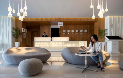 a woman sitting at a table with a laptop in a lobby at Novotel Jeddah Tahlia in Jeddah