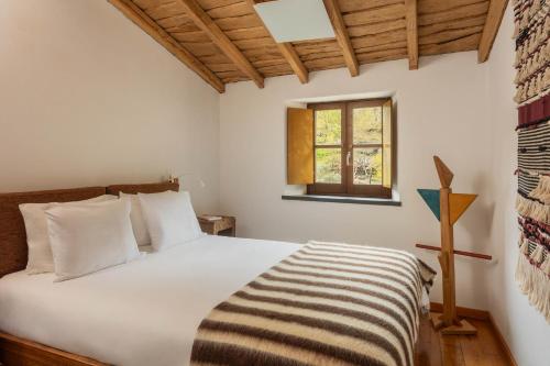 a bedroom with a large white bed with a window at Cerdeira - Home for Creativity in Lousã