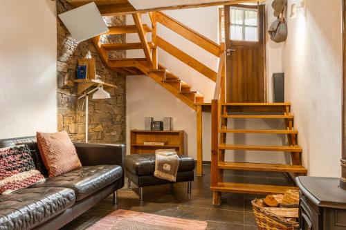 a living room with a leather couch and a wooden staircase at Cerdeira - Home for Creativity in Lousã