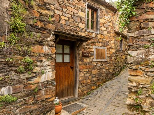 an old stone building with a wooden door on it at Cerdeira - Home for Creativity in Lousã