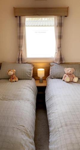 two beds in a bedroom with two teddy bears at Lakeside East 16 - Haggerston Castle in Berwick-Upon-Tweed