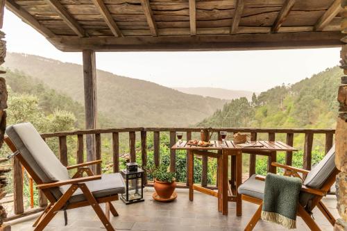 a porch with a table and chairs and mountains in the background at Cerdeira - Home for Creativity in Lousã