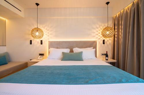 1 dormitorio con 1 cama grande y 2 luces colgantes en Pegasos Deluxe Beach Hotel en Faliraki