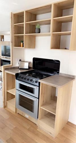 a kitchen with a stove and wooden cabinets at Lakeside East 16 - Haggerston Castle in Berwick-Upon-Tweed
