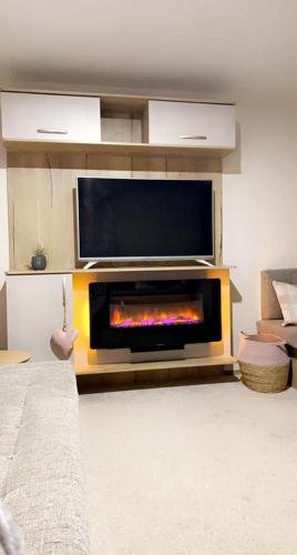 a living room with a fireplace with a flat screen tv at Lakeside East 16 - Haggerston Castle in Berwick-Upon-Tweed