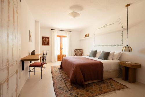 a bedroom with a bed and a table and a desk at Petunia Ibiza, a Beaumier hotel in Cala Vadella