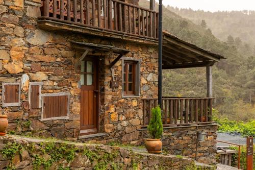 an old stone house with a porch and a balcony at Cerdeira - Home for Creativity in Lousã