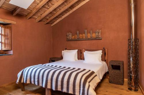 a bedroom with a bed with a striped blanket at Cerdeira - Home for Creativity in Lousã