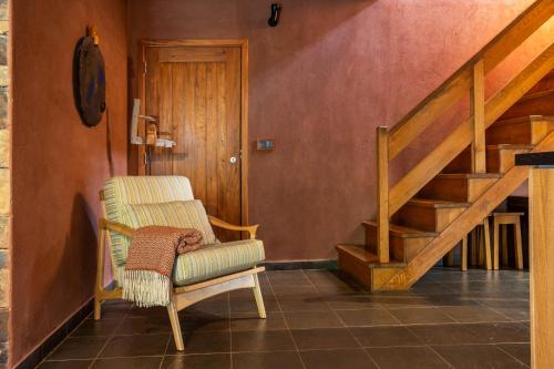 a living room with a chair and a staircase at Cerdeira - Home for Creativity in Lousã