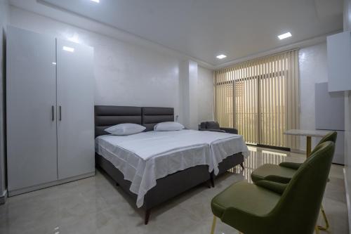 a bedroom with a bed and two green chairs at Gama Palace in Batumi