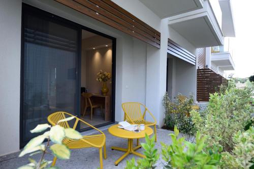 a patio with two chairs and a yellow table and chairs at Falena Luxury Rooms in Kalyves Poligirou
