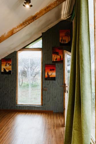 Habitación con ventana grande y cortina verde. en Kilimanjaro view cabin-Amboseli, en Oloitokitok 